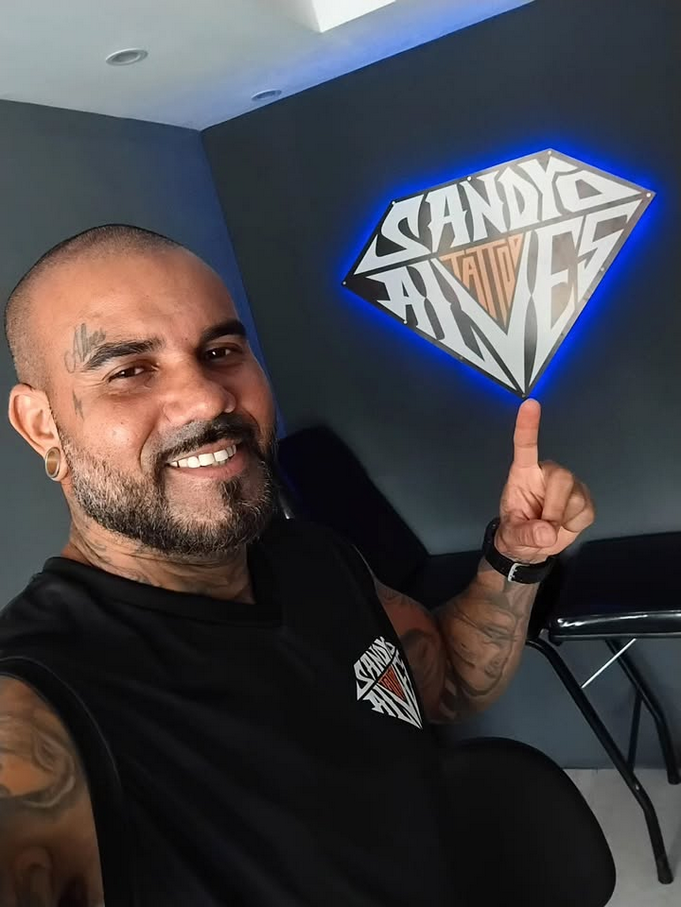 Sandro Alves no seu estúdio apontando para sua marca