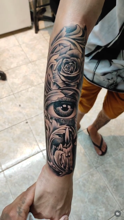 Tatuagem de rosa com olho realista e vela no antebraço