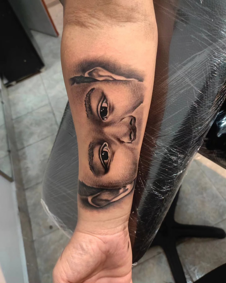 Tatuagem de retrato realista de um menino no antebraço